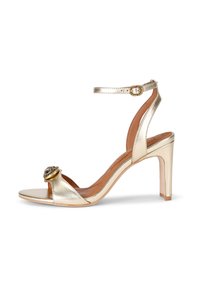 Złote metaliczne sandały na wysokim obcasie z otwartym noskiem, paskiem na kostkę i dekoracyjną okrągłą ozdobą z przodu. Gładkie wykończenie.