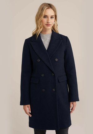 Navy wool double-breasted coat with notched lapels, black buttons, and side pockets, featuring a straight fit and long sleeves.