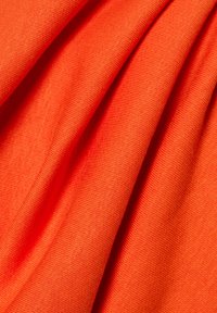 Tessuto arancione vivace caratterizzato da una superficie liscia, con pieghe drappeggiate che rivelano un materiale leggero e elastico adatto per l'abbigliamento.