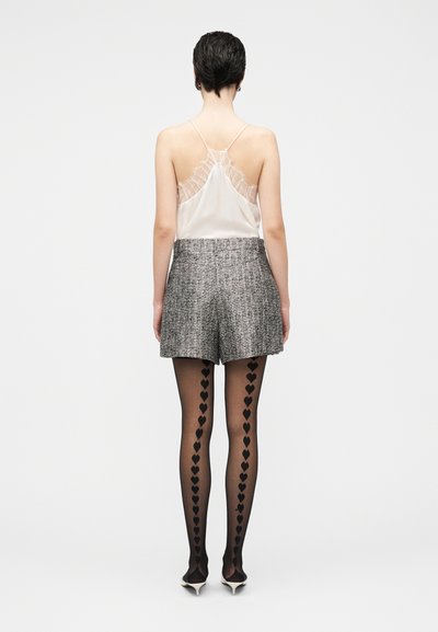 Silk camisole with lace detail, grey tweed shorts, and black tights featuring heart patterns, paired with pointed-toe heels.