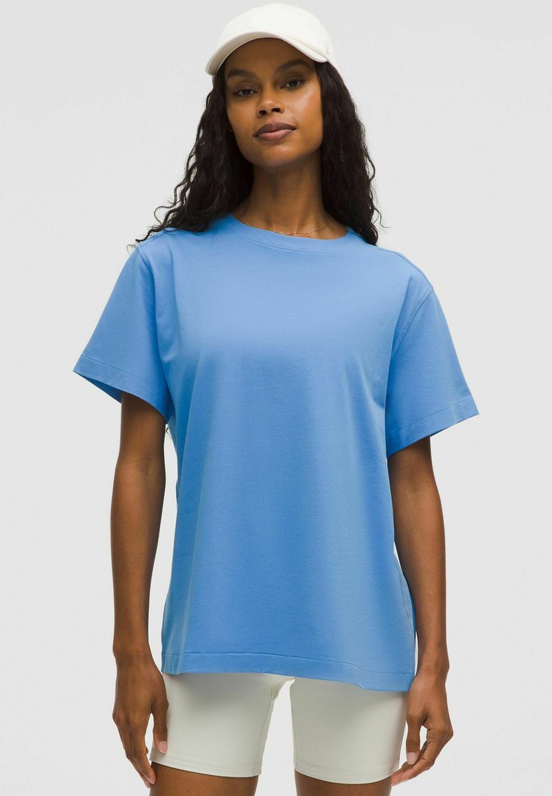 Ljusblå t-shirt med kort ärm gjord av slät tyg med rund halsringning, ihop med ljusa shorts.