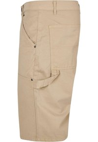 Beige cargo šortky vyrobené z bavlněné tkaniny, s několika kapsami, uvolněným střihem a knoflíkovými detaily. Hladký povrch s prošitými detaily.