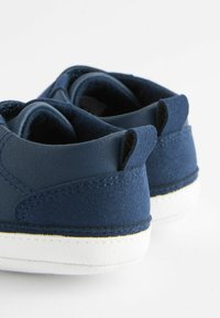 Baskets bleu marine avec une finition en cuir lisse et en suède texturé, dotées de semelles en caoutchouc blanc et de petites languettes à l'arrière pour un enfilage facile.