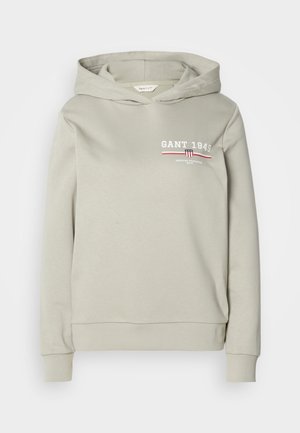 Kappuhoodiga helesinises materjalis, millel on eespool logo "GANT 1949" valge ja punasega. Sisaldab ribaga mansette ja alumist äärt. Pehme tekstuur.