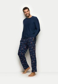 Granatowa bluzka z długim rękawem i wzorzyste piżamowe spodnie z niedźwiedziami na kratkowanym tle. Spodnie mają elastyczną talię i kieszenie boczne.