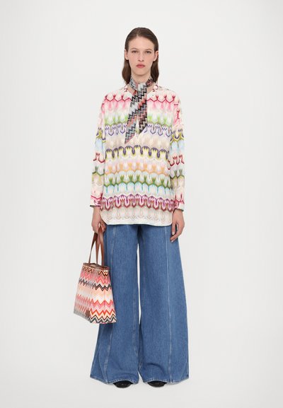 Cămașă lungă cu mânecă, colorată și cu un model, cu guler; asortată cu pantaloni din denim cu picioare largi și o geantă cu model zigzag în nuanțe de corai și maron.