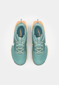 Teal and orange athletic shoes with a mesh upper, textured detailing, and a white Nike swoosh. Features a cushioned sole and lace-up design.