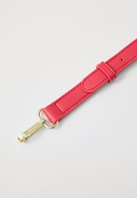 Bracelet en cuir rose avec une texture lisse, doté d'un fermoir en métal doré et d'un passant réglable. Des bords soigneusement cousus renforcent la durabilité.
