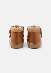 Brune lær høy-top sneakers med tan semsket skinn detaljer og myk grå plysj fôring, med en teksturert gummisåle og rund form.