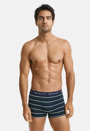 Boxer da uomo con vita blu navy che presenta il logo GANT ripetuto. Il tessuto è elasticizzato, con strisce blu scuro, verdi e bianche.