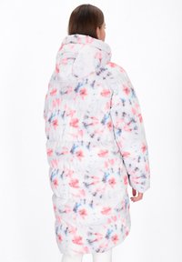 Lange, weiße Pufferjacke mit pinken, blauen und grauen Batikmustern, ausgestattet mit einer Kapuze und gestepptem Material zur Isolierung.