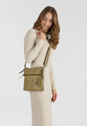 Borsa a tracolla in pelle verde oliva con chiusura a zip, tasca frontale e emblema dell'ancora. Presenta una tracolla regolabile e una superficie liscia.