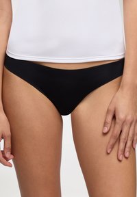 Biancheria intima nera in stile bikini realizzata in tessuto morbido con un design a vita bassa, caratterizzata da una vita senza cuciture e una copertura minima.