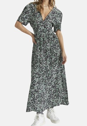 Robe maxi avec un motif paisley noir et menthe, décolleté en V, manches courtes et taille cintrée, assortie à des baskets blanches.
