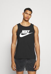 Sort bomulds tanktop med et stort hvidt Nike-logo på forsiden. Designet inkluderer brede ærmegab og en rund udskæring.