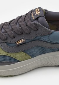 Vans sneakers med en blanding av mørkegrå, grønn og blå materialer. Teksturert semsket skinn og nettverksoverdel, med gummisåle og logo-detall.