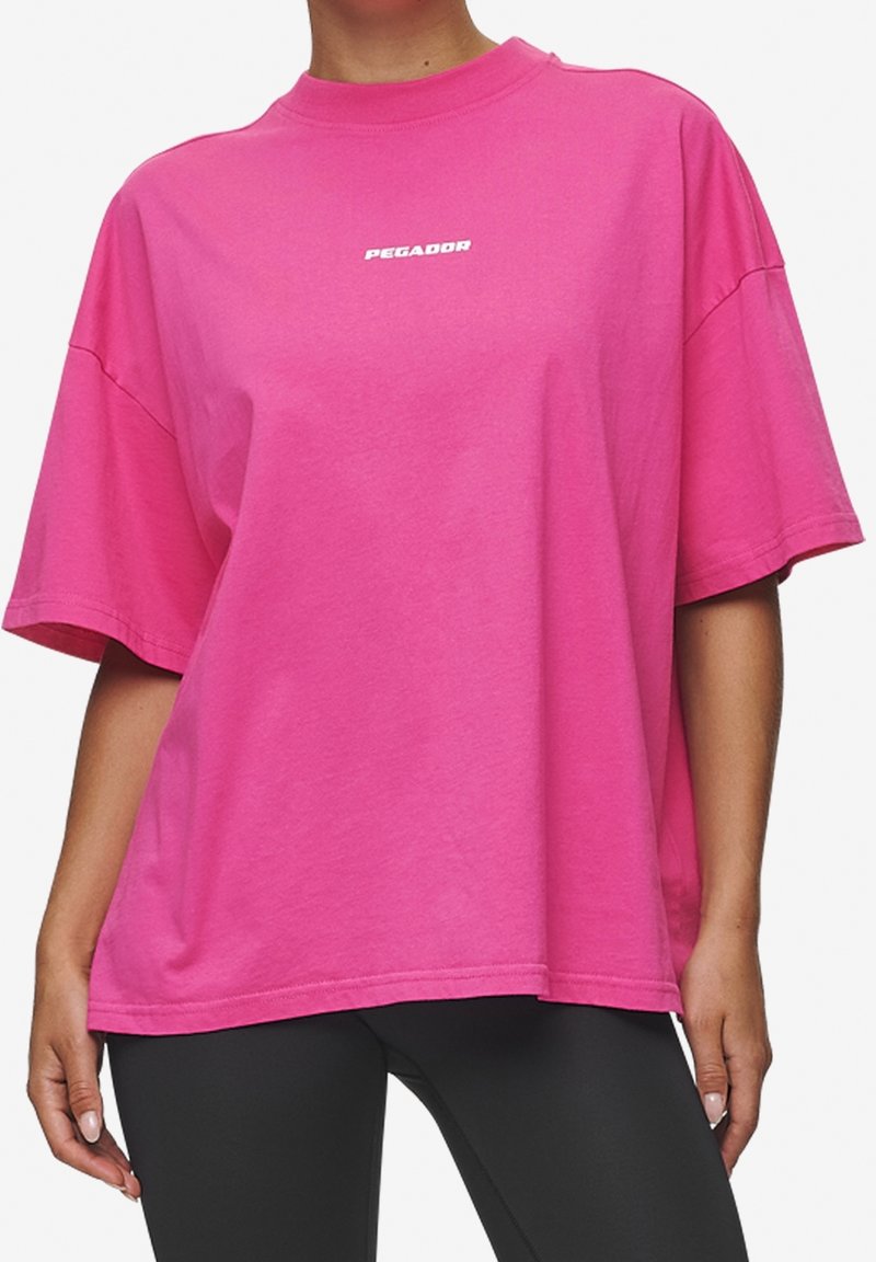 Rosa oversized t-shirt i bomull med rund halsringning. Har korta ärmar och en liten vit "PEGADOR"-logotyp framtill.