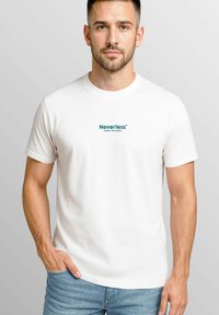 Weißes Baumwoll-T-Shirt mit rundem Halsausschnitt, kurzen Ärmeln und tealfarbenem Text "Neverless Sunday Volleyball" auf der Brust.