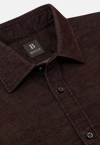 Brun texturerad skjorta med en skarp krage, två svarta knappar och en etikett som läser "BOGGI MILANO." Har vertikal ribbning genom hela skjortan.