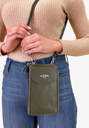 Olivgrön läder crossbody-väska med en framflik, dragkedjestängning och guldfärgad hårdvara. Strukturerad yta, kompakt design och justerbar rem.