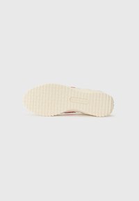 Talpa de sneaker din cauciuc în crem, cu un model texturat pentru aderență, având o dungi roșie și detalii cu logo embossat.