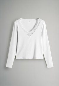 Biely top s dlhým rukávom z textúrovaného materiálu, s hlbokým výstrihom do V lemovaným kvetinovou čipkou. Skrátený strih.