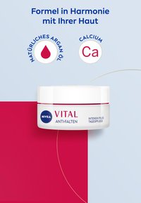 NIVEA VITAL anti-wrinkle cream in a round white container with a pink accent band, featuring text on a blue and pink background.
