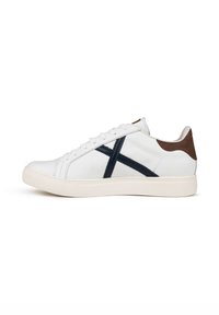 Sneaker in pelle bianca con design incrociato blu navy, dettaglio del tallone marrone e suola in gomma bianca. Presenta punta rotonda e chiusura con lacci.
