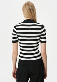 Svart- och vitrandig kortärmad topp med ribbad textur och figurnära silhuett, med rund hals och subtila sömmar.