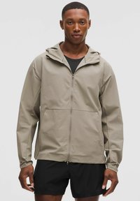 Leichtgewichtige beige Jacke mit Kapuze, Frontreißverschluss und Taschen. Das Design ist einfach und verfügt über eine glatte Textur im lässigen Stil.