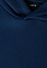 Granatowa bluza z kapturem wykonana z miękkiego, teksturowanego materiału, z kapturem na sznurek i metką z napisem „LMTD” przy kołnierzu.