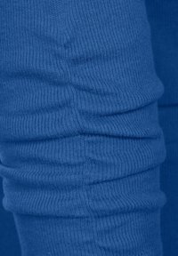 Blå ribbad tyg med en strukturerad yta, som visar veck och veck, vilket indikerar ett mjukt, stretchbart material, lämpligt för kläder.