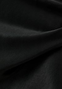 Slät, svart tyg med en silkig textur, med en lätt glans och mjuk fall. Lämplig för kläder eller möbelklädsel.