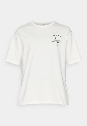 Balta medvilnė marškinėliai su trumpomis rankovėmis, su juodu gervės grafiniu atvaizdu ir tekstu „JAPONIJA“ kreivai išdėstytu kairėje krūtinės pusėje.