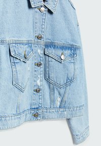 Chaqueta de mezclilla azul claro que presenta un cierre frontal con botones, dos bolsillos en el pecho, detalles desgastados y acentos de costura en contraste.
