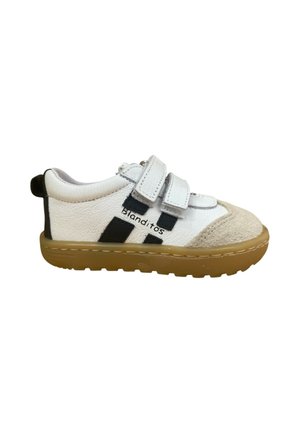 Zapatilla blanca con acentos negros, correas de velcro y una punta texturizada en color marrón. Cuenta con una suela de caucho duradera y el nombre de la marca "blanditos" en un lado.