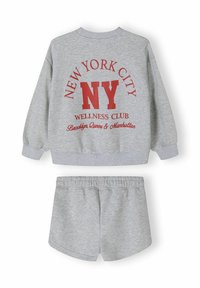 Grijze trui en shortset. De trui heeft rode tekst "NEW YORK CITY" en "WELLNESS CLUB", met ribbels aan de mouwen. Zacht katoenmateriaal.