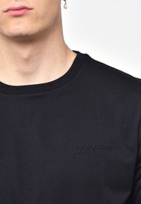 T-shirt in cotone nero con scollatura rotonda e ricamo sottile di RefrigiWear dello stesso colore nell'area del petto sinistro.