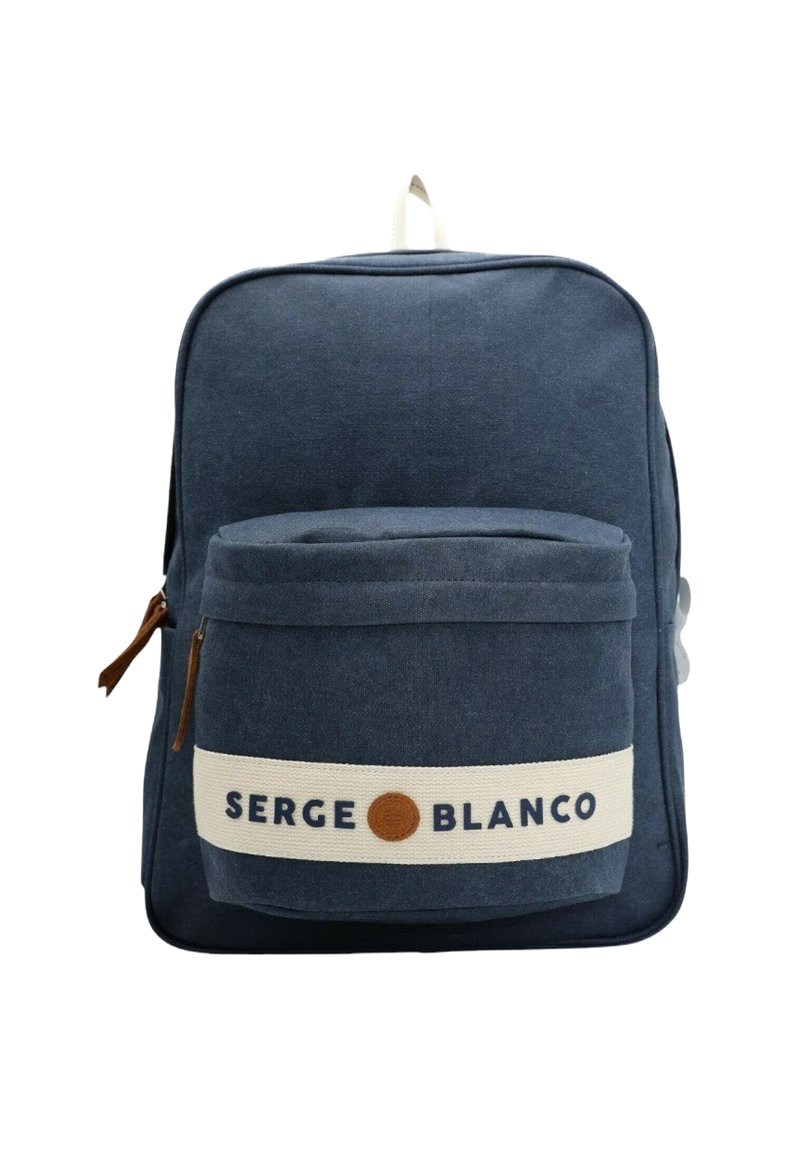 Sac à dos en toile marine avec une poche avant, une sangle beige et un détail de logo. Il présente une texture lisse et une fermeture éclair.