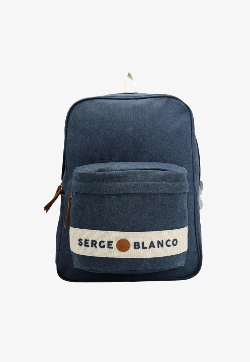 Sac à dos en toile marine avec une poche avant, une sangle beige et un détail de logo. Il présente une texture lisse et une fermeture éclair.