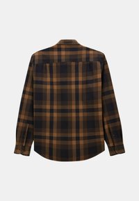 Chemise à manches longues à carreaux bruns et noirs avec des poignets boutonnés, un détail de yoke au dos et une texture de tissu lisse.