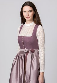 Purple dirndl with a fitted bodice, square neckline, and button detail. Features a satin skirt and lace long-sleeve top, cinched with a ribbon.
