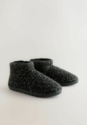 Black ankle-height slippers made of textured fabric with a speckled pattern, featuring a flexible rubber sole and rounded toe design.
