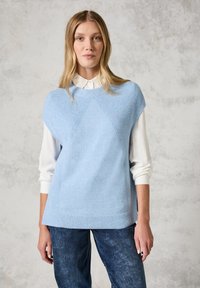 Jasnoniebieski sweter w dzianinę z teksturalnymi akcentami, bezrękawnik z okrągłym dekoltem, nałożony na białą koszulę z kołnierzykiem.