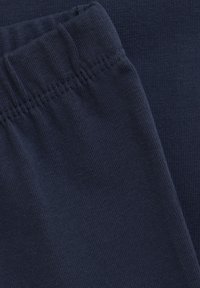 Marinblå bomullstyg med ribbat mönster, som har en elastisk midja och fina sömdetaljer längs kanterna.