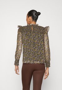 Blusa nera floreale con lunghe maniche trasparenti, spalle arricciate e dettaglio a chiave sul retro. Presenta un mix di piccoli fiori gialli e rosa.