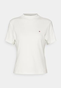 Bílý tričko s krátkým rukávem a vysokým výstřihem. Obsahuje malé vyšívané logo v červené a modré barvě na levé části hrudi. Bavlněný materiál.