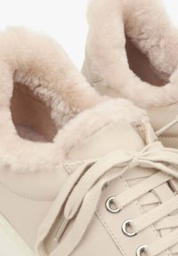 Helle beige Sneaker mit weichem Kunstfellfutter am Schaft, flachen Schnürsenkeln und silbernen Ösen. Glatte Lederoberfläche und runde Zehenform.