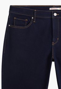 Mörkblå denim jeans med kontrasterande guldstickningar, femficksdesign, frontknäppning och rakt ben.