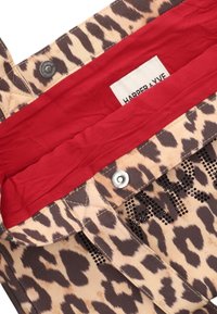Tissu imprimé léopard avec une texture lisse, doté d'une doublure intérieure rouge vif et d'une fermeture à pression. Comprend une étiquette de la marque "HARPER & YVE."